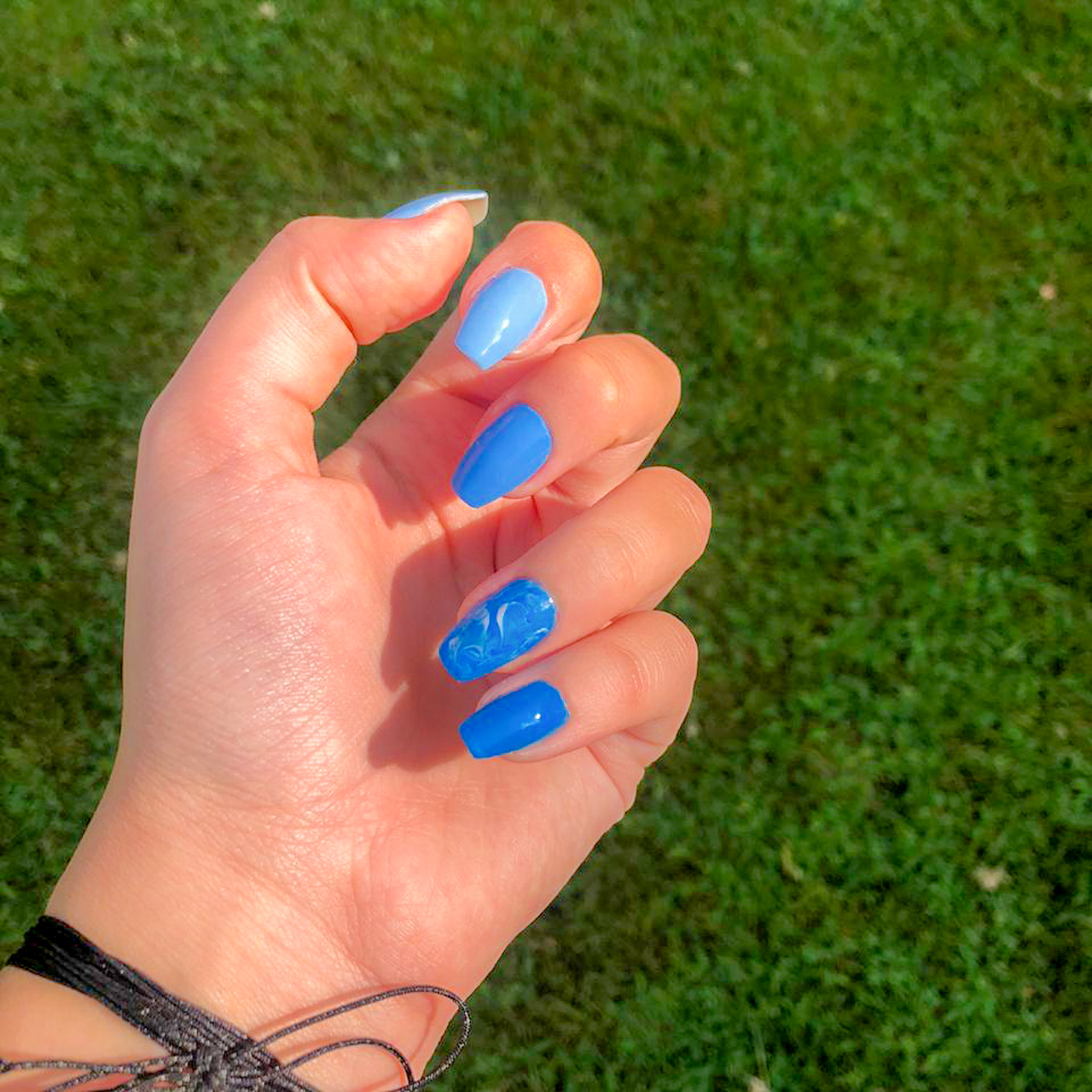 Blue ombré nail design fading from light to dark tones with glossy finish