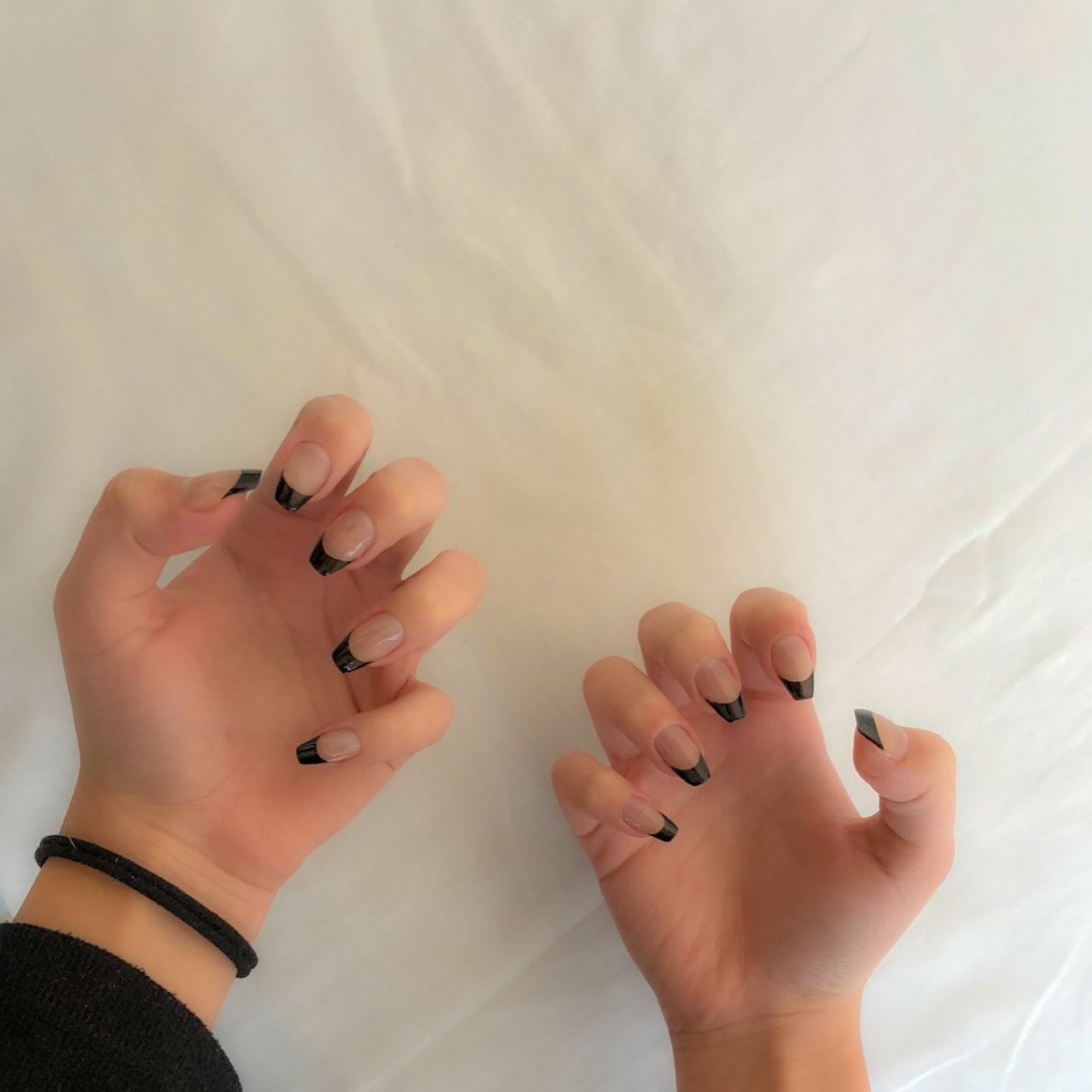 Clear base nails with bold black French tips in a sleek, contemporary style